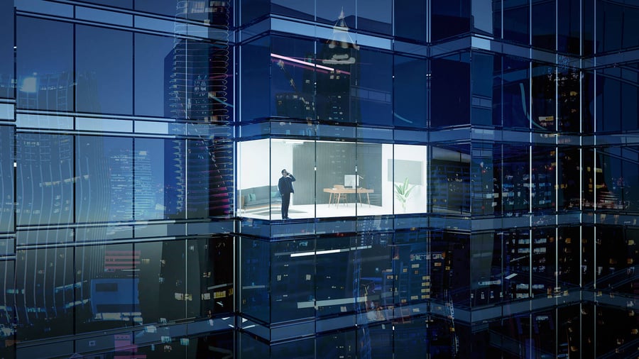 Night-time closeup of a modern, office sky-rise and only one office is lit and there's a businessman inside making a call.
