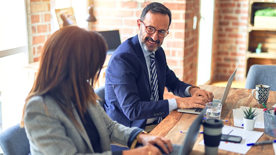 2 diverse, high-level execs confidently look at each other as they prepare for a meeting