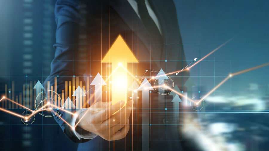 Body of a business person with hand extended to the foreground and reaching toward a graph of rising stocks and grabs at the brightest & largest golden arrow of the graph