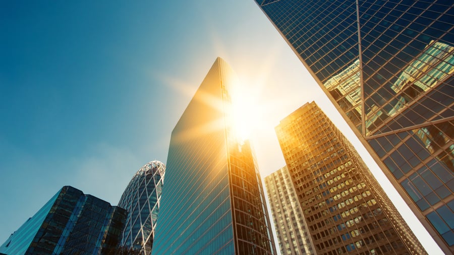 Close up, ground view of a series of skyscrapers and then sun is intensely piercing in between them